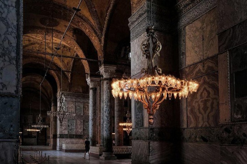 An ornate chandelier, marble columns, and a person walking in a grand hall. 3