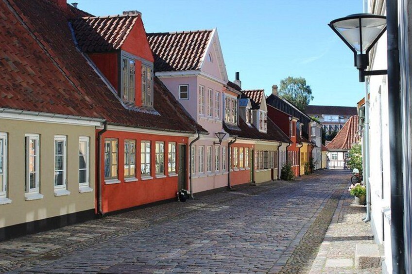 A cobblestone street lined with colorful buildings, a clear sky, and a street lamp. 1
