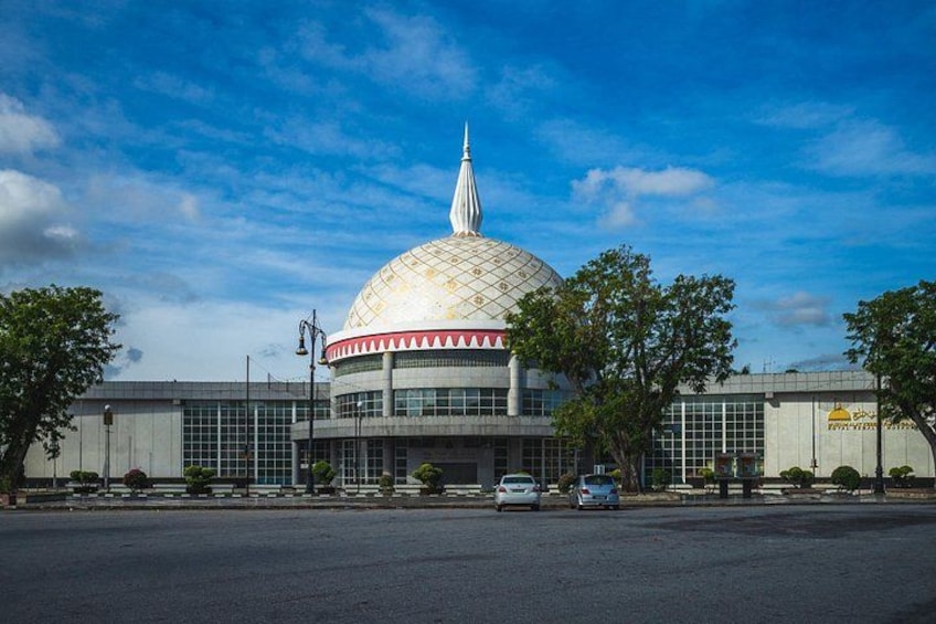 A large domed building with a spire, surrounded by trees and a clear sky. 5
