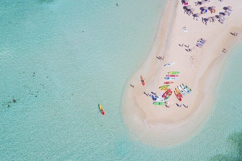 An aerial view of a beach with people and colorful kayaks. 1