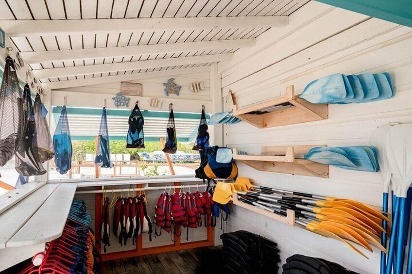 A boat interior with life jackets, paddles, and a netted area. 4