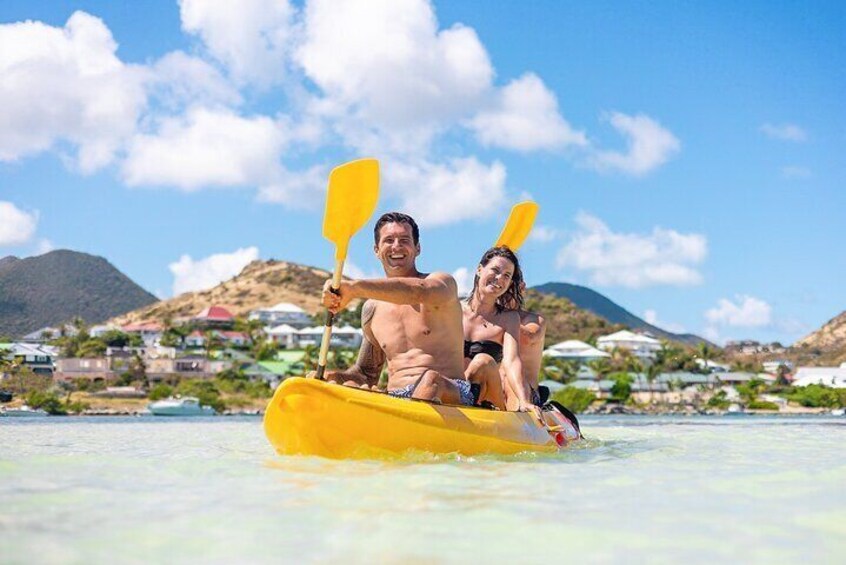 Two people kayaking on a calm sea with a mountainous landscape in the background. 3