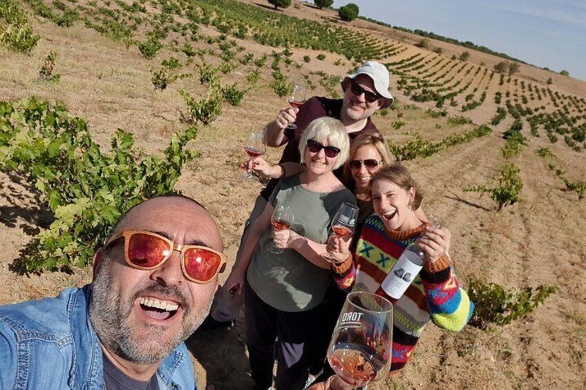Un gruppo di persone in un vigneto che sorseggia vino da calici. 1