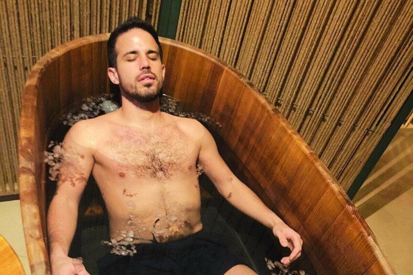 A person sitting in a wooden tub with water. 3