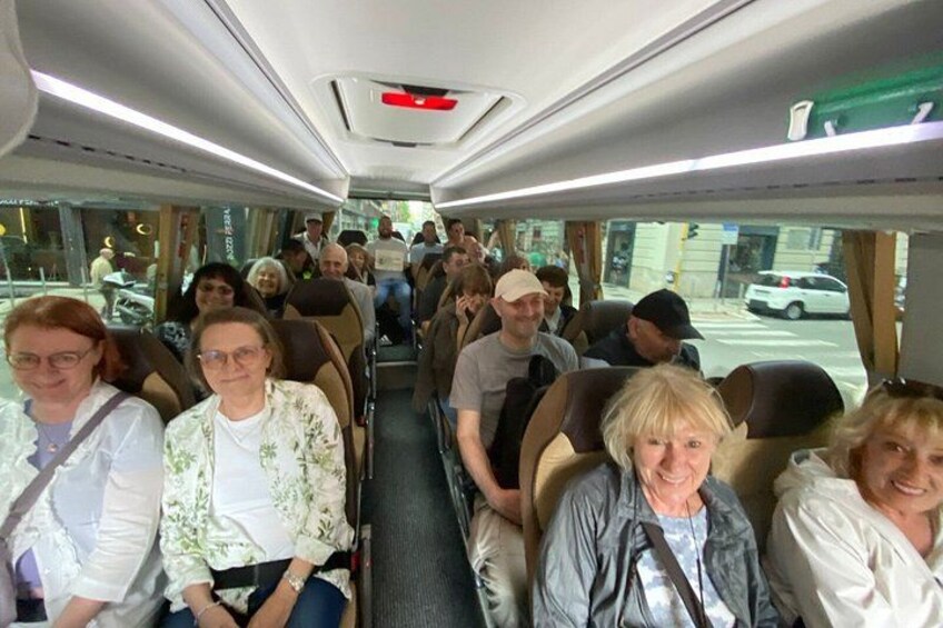 Interior de autobús con pasajeros sentados, ventanas que muestran vistas de la calle y compartimentos superiores. 3