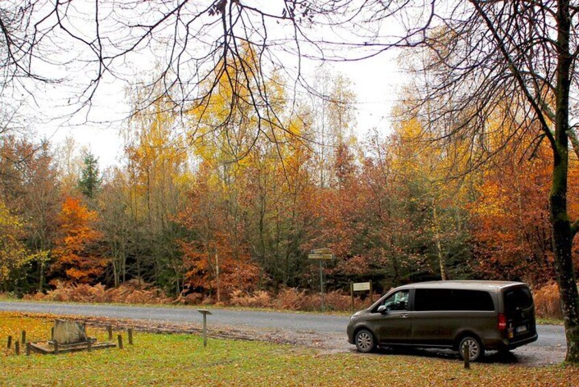 A van parked on a road with autumn-colored trees in the background. 3