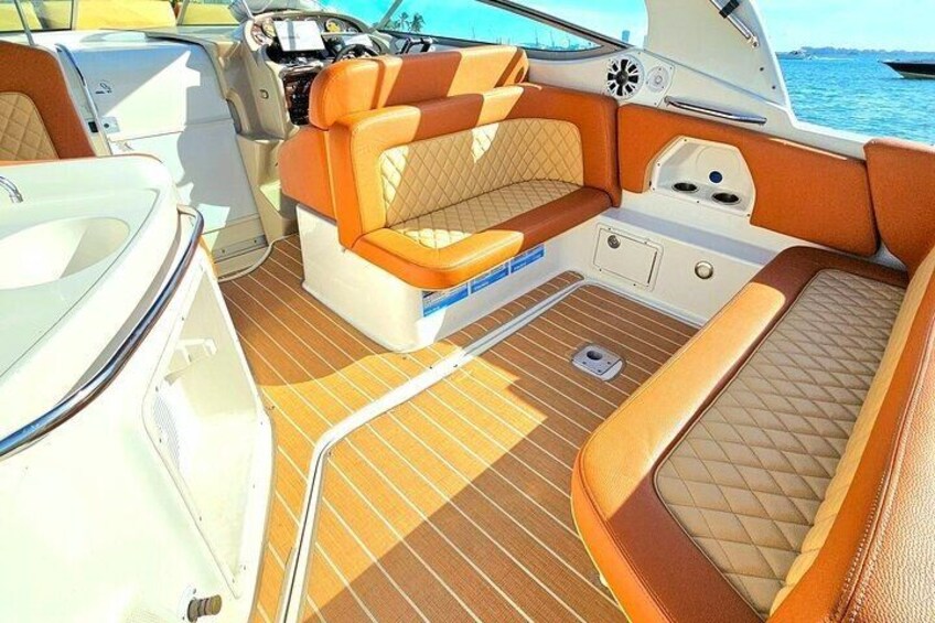 A boat interior with cushioned seating, a steering wheel, and a control panel. 4