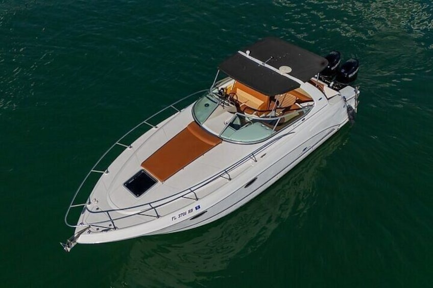 A white motorboat with a brown deck and a cabin, floating on calm water. 2