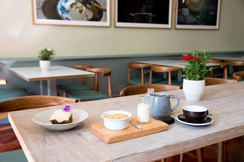 A wooden table with a plate of food, a jug of milk, a cup, and a small pitcher. 2