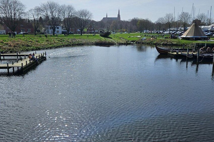 Un río tranquilo con un muelle de madera, un bote pequeño y un área de césped con una carpa. 3