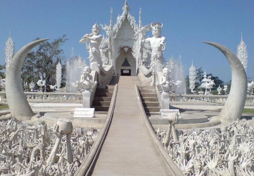 Una entrada imponente con una escalera que conduce a una estructura similar a un templo, rodeada de numerosas estatuas y detalles intrincados. 2