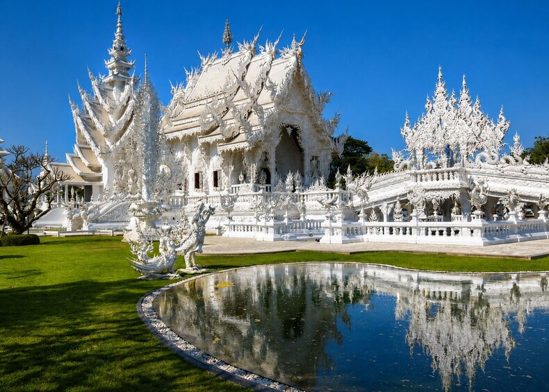 Un templo blanco ornamentado con intrincados grabados y un estanque que refleja el entorno. 5