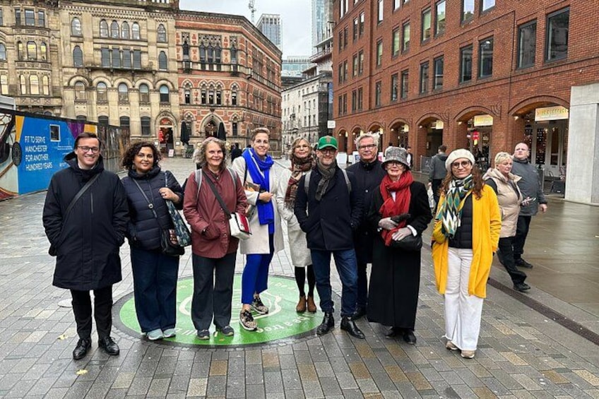 Een groep mensen staat op een stadsplein met historische gebouwen op de achtergrond. 3