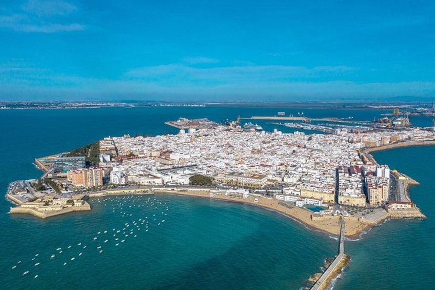 Vista aérea de una ciudad costera con una zona urbana densa, un puerto deportivo con barcos y un faro destacado. 2
