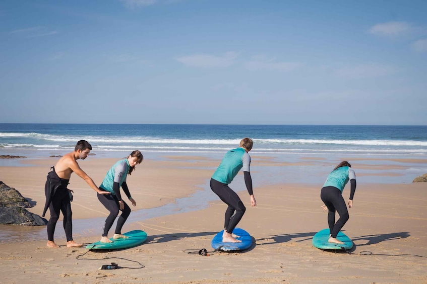 Cuatro personas en la playa con tablas de surf, preparándose para surfear. 2