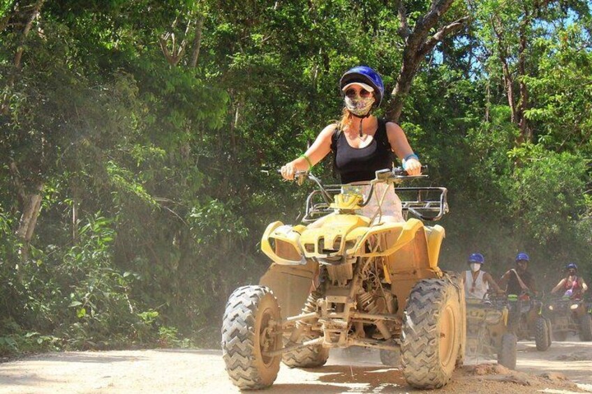 Eine Person fährt mit einem Quad auf einem unbefestigten Weg, umgeben von Bäumen. 3