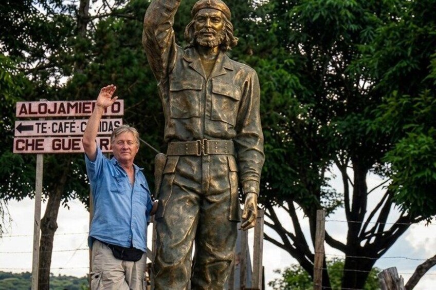 A person standing next to a statue with a signpost in the background. 3