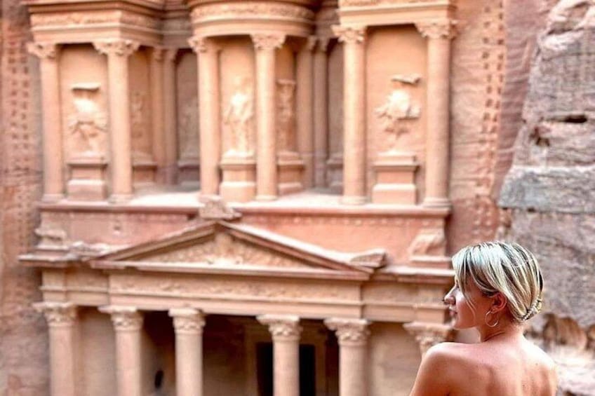 A person standing in front of a historical building with columns and intricate carvings. 3