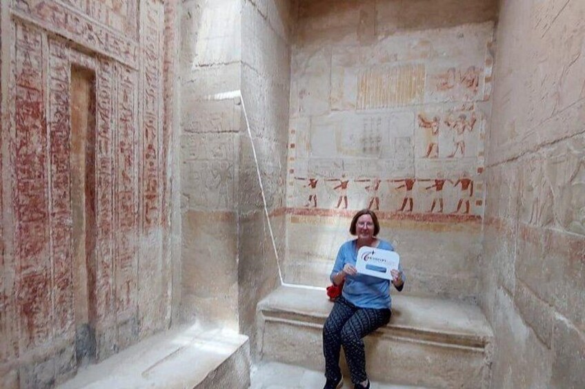 A person sitting on stone steps in an ancient Egyptian temple with hieroglyphs on the walls. 4