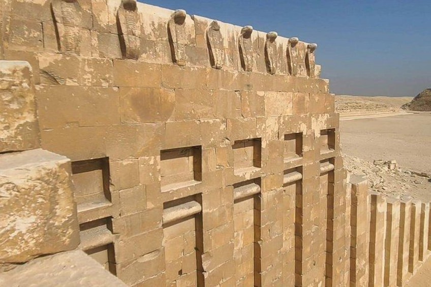 A stone wall with rectangular openings and a desert landscape in the background. 2
