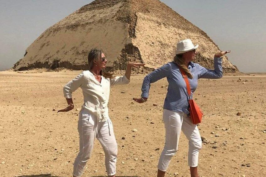 Two people in a desert with a pyramid in the background. 3