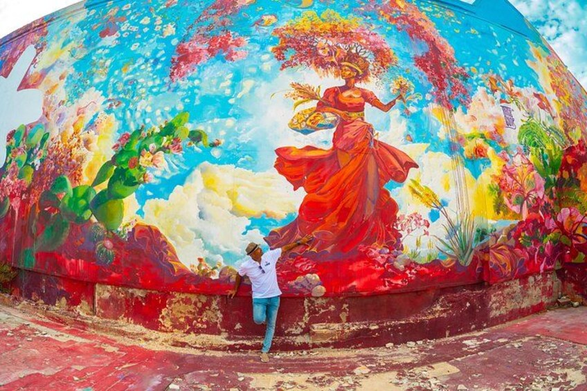 Une fresque représentant une femme vêtue d’une longue robe flottante, des cactus et des fleurs. 2