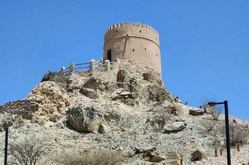 Une tour de pierre historique, située sur une colline au terrain rocheux et à la végétation clairsemée. 5