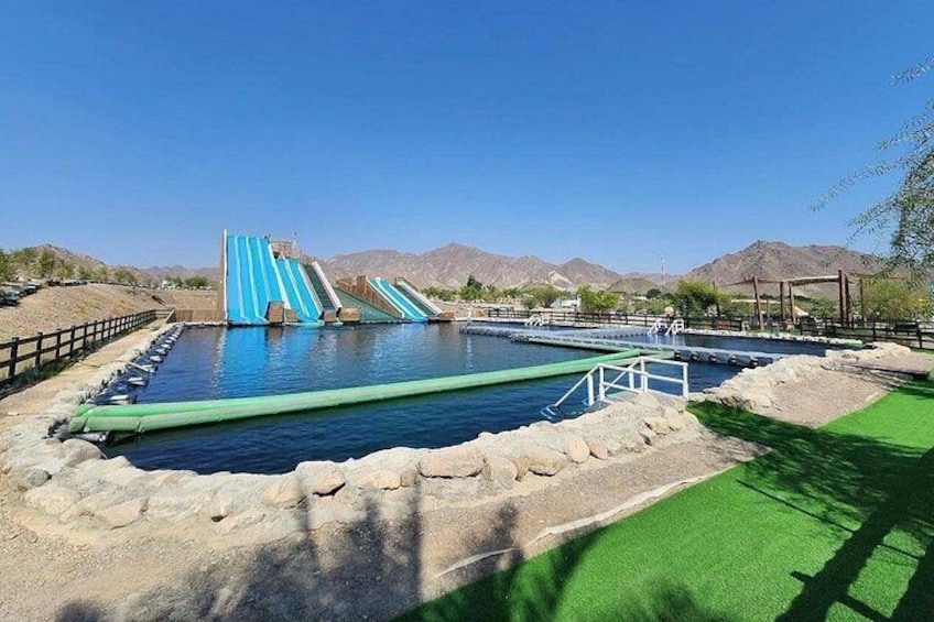 A water park with a large pool, a blue slide, and a green artificial turf area. 4