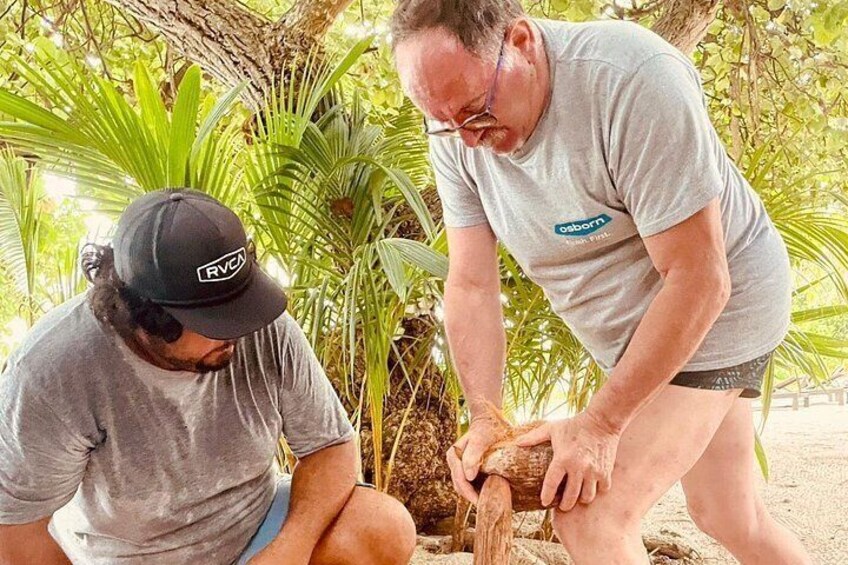 Two people outdoors, one cutting a log with a saw. 2