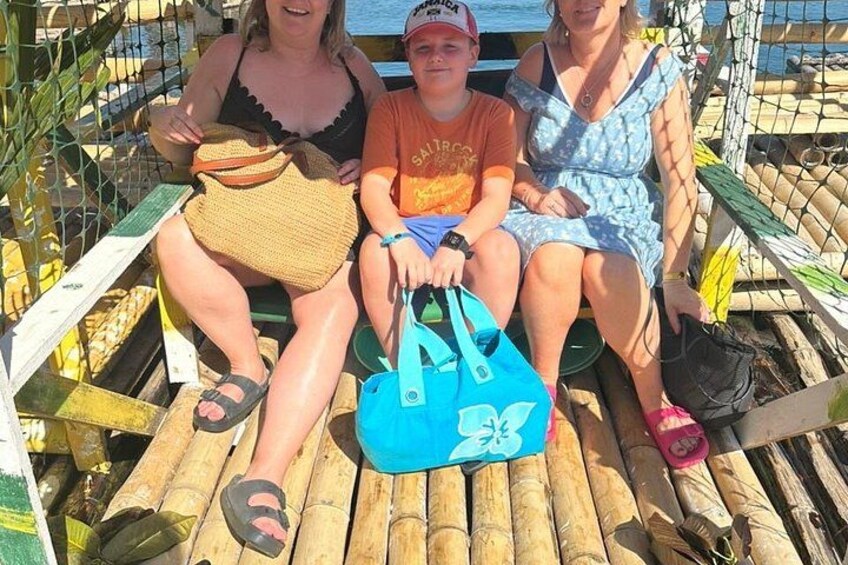Three people sitting on a wooden bench with a blue bag in between them. 5