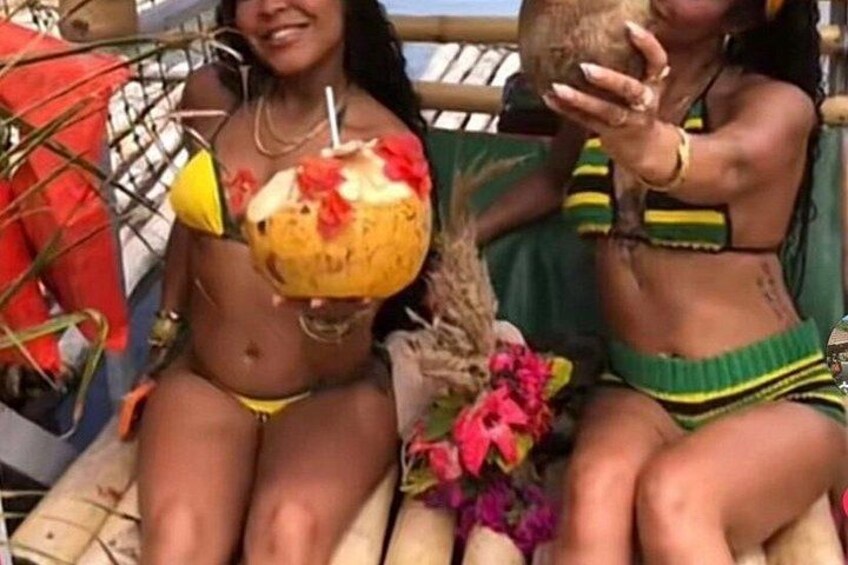 Two people in bikinis holding coconuts with straws. 2