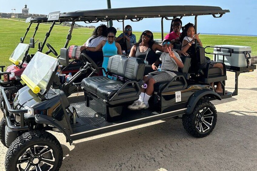 A golf cart with passengers on a golf course. 3