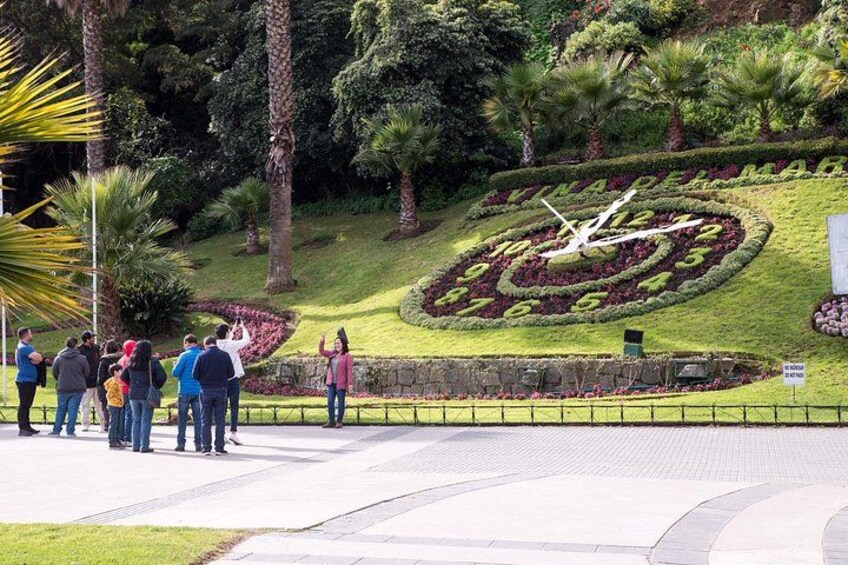 A landscaped garden with a clock, people, and a pathway. 2