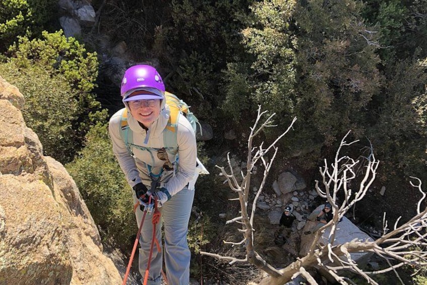 Una persona descendiendo por un risco rocoso con casco y arnés. 2