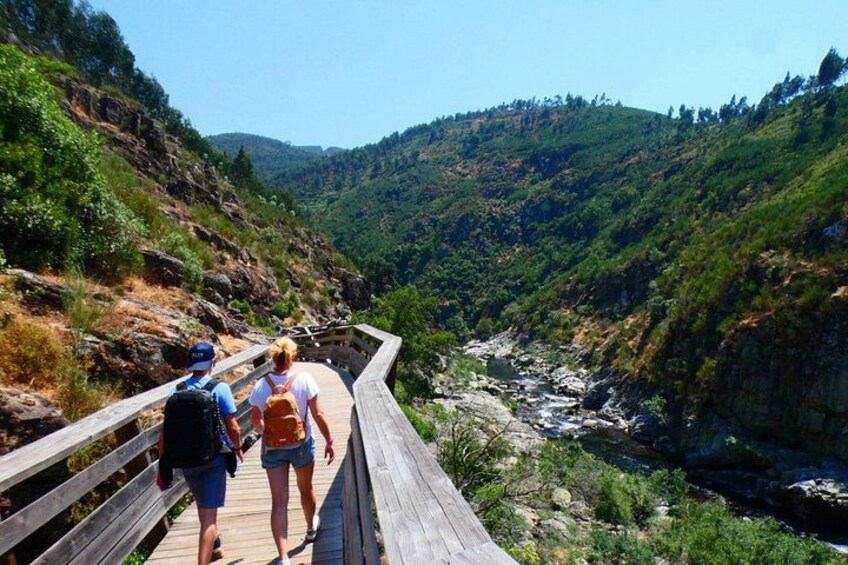 A wooden boardwalk along a river with hikers. 3