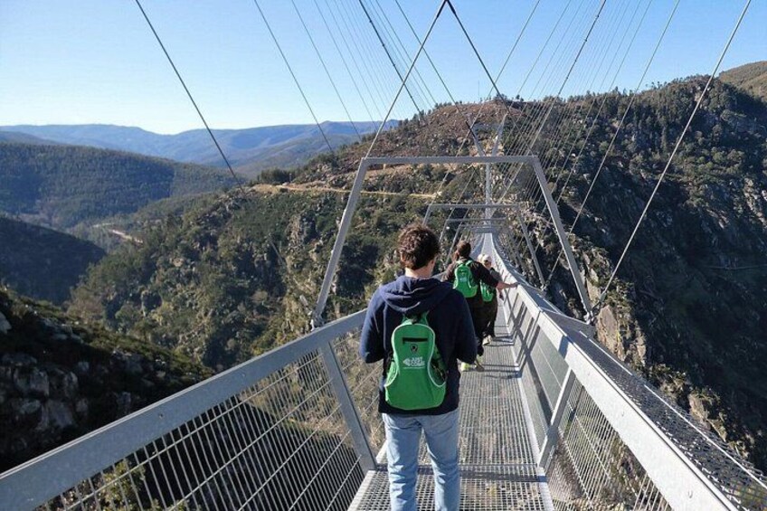 A suspension bridge with hikers walking on it, surrounded by mountainous terrain. 1
