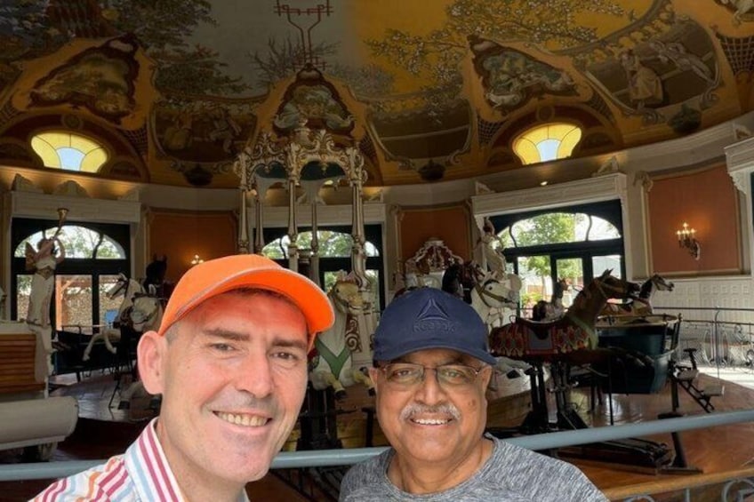 Two people in a room with ornate ceiling artwork and a carousel. 3