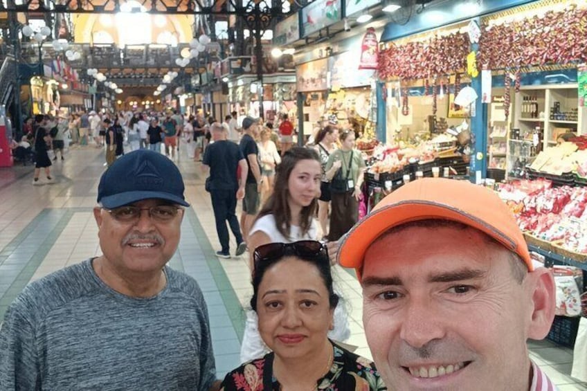 A busy indoor market with people shopping and vendors selling goods. 2