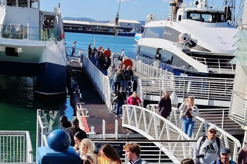 A busy pier with people boarding and disembarking boats. 2