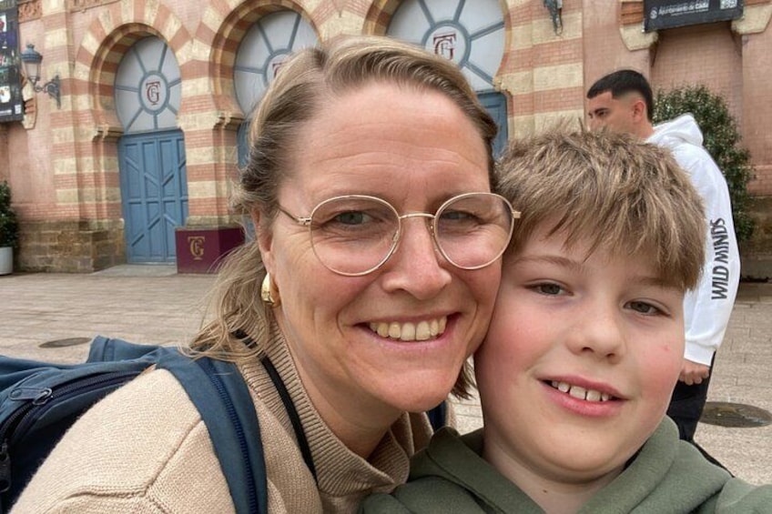 Une personne porte un sac à dos et se tient devant un enfant, devant un bâtiment doté de fenêtres en arc de cercle et d’une porte bleue. 3