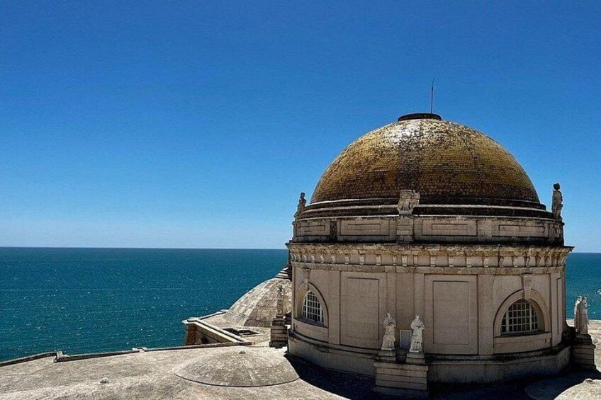 A domed building with statues, overlooking a body of water. 2