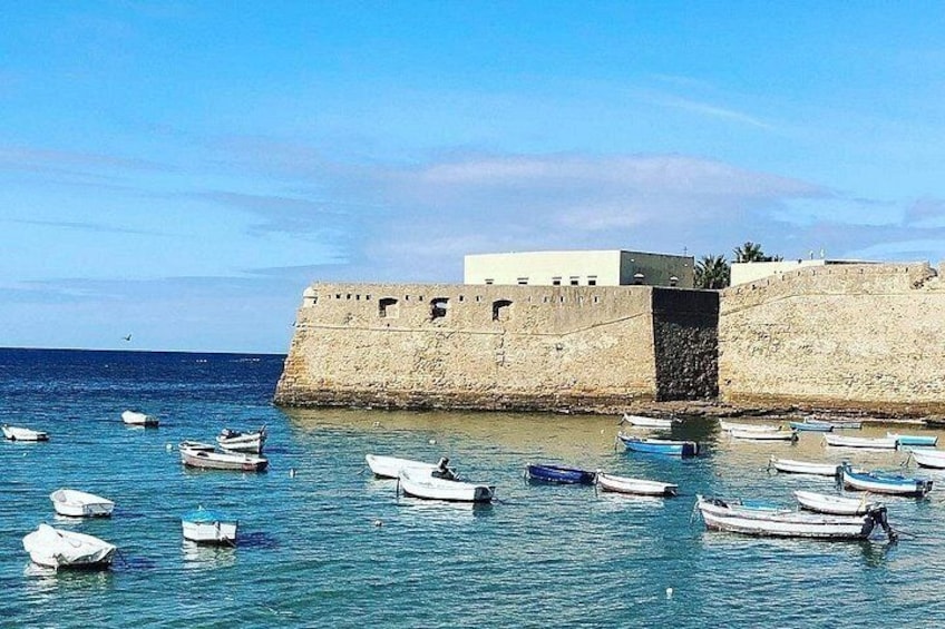 Une fortification côtière avec plusieurs petits bateaux amarrés dans l’eau. 2