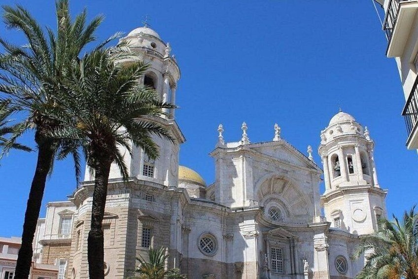 Eine historische Kirche mit zwei Glockentürmen und einer Kuppel, umgeben von Palmen. 1