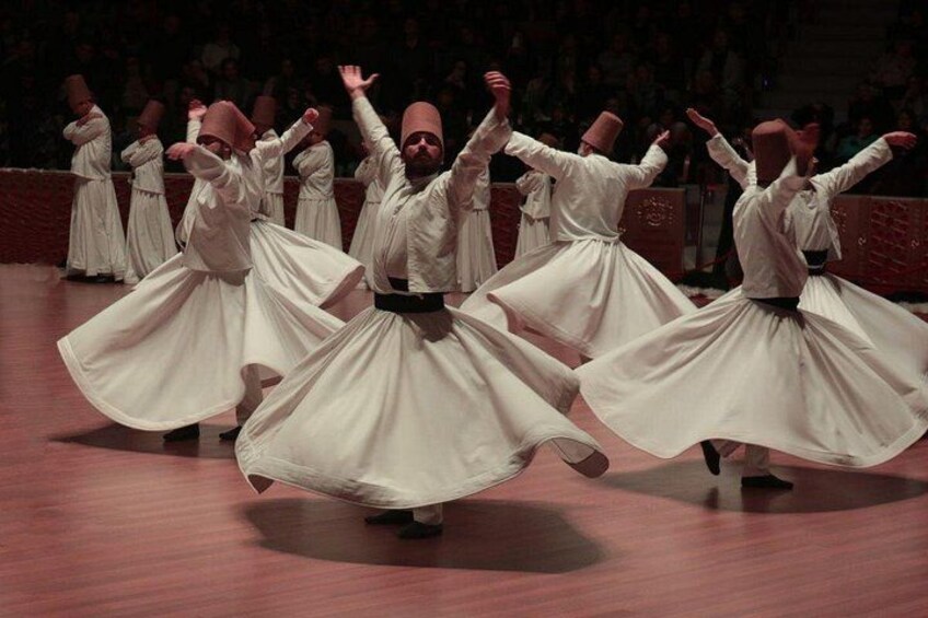 A group of dancers in white costumes performing on a stage. 1
