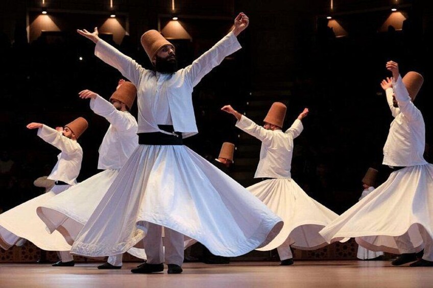 A group of dancers in white costumes performing a dance with large white skirts. 4