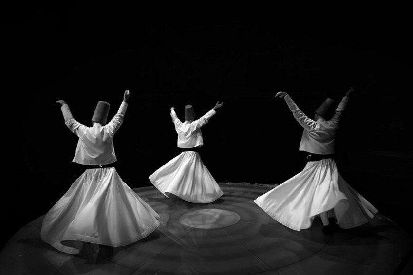 Three dancers in white costumes performing on a stage. 2