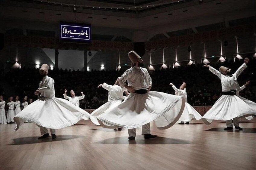 A dance performance with dancers in white attire on a stage. 5