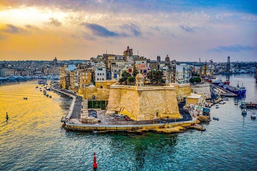A coastal cityscape with a prominent fort, a harbor with boats, and a sunset sky. 2