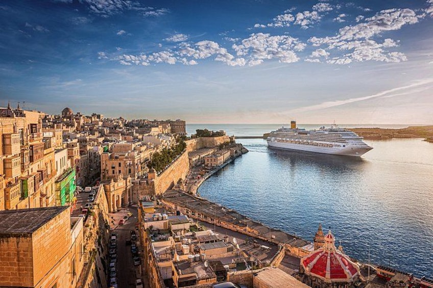 A coastal city with historic buildings, a large cruise ship docked at the port, and a prominent red-domed structure. 4