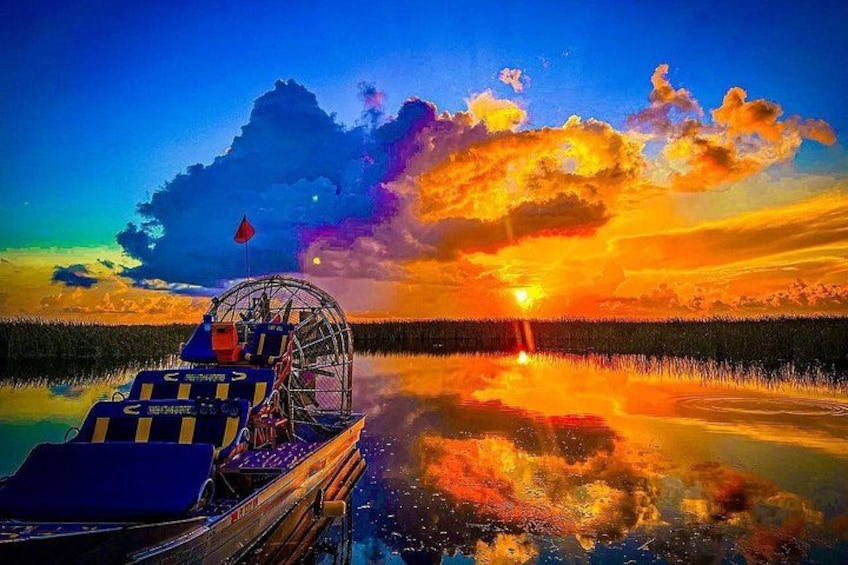 Een boot met een luifel, een zonsondergang en een rustig wateroppervlak dat de lucht weerspiegelt. 2